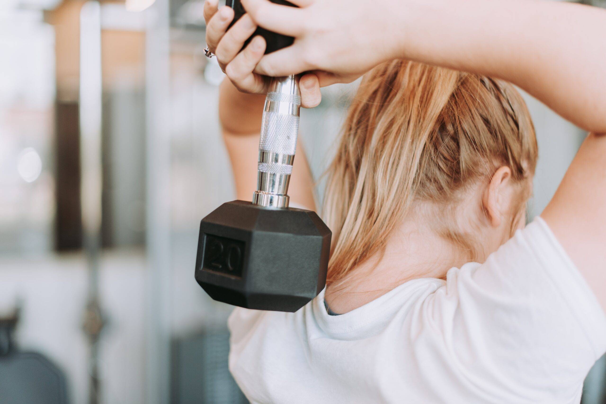 Woman doing an overhead triceps extension with a dumbbell in the gym