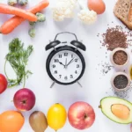 Variety healthy ingredients with an alarm clock arranged against an isolated white background.