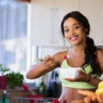 Fit Woman Holding Gray Steel Spoon and eating healthy oat meal.