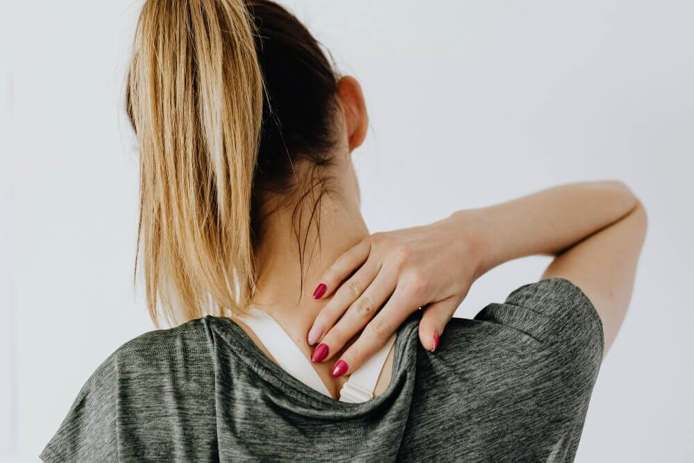 Woman holding her neck and shoulder with muscle soreness