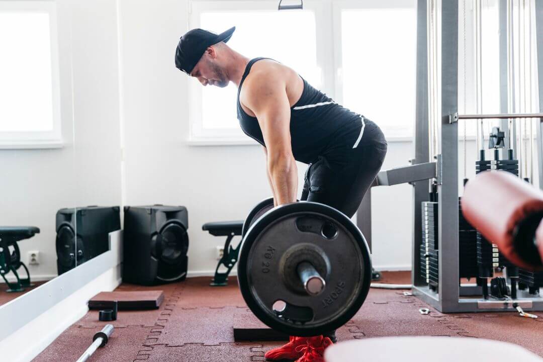 Man performing a Romanian deadlift with a loaded barbell in a gym
