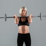 Confident blond fit woman lifting barbell