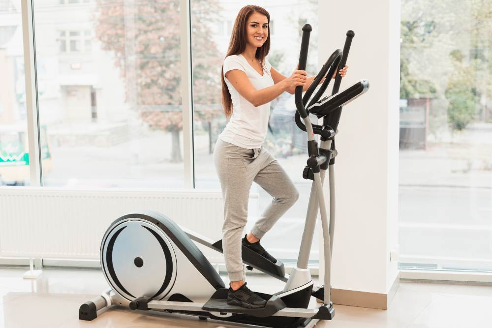 Woman exercising on an elliptical trainer in a bright room