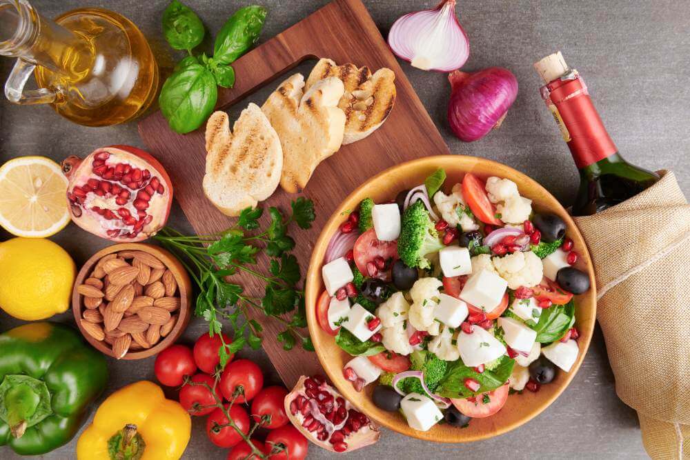 Greek salad with feta and olives surrounded by vegetables, olive oil and wine