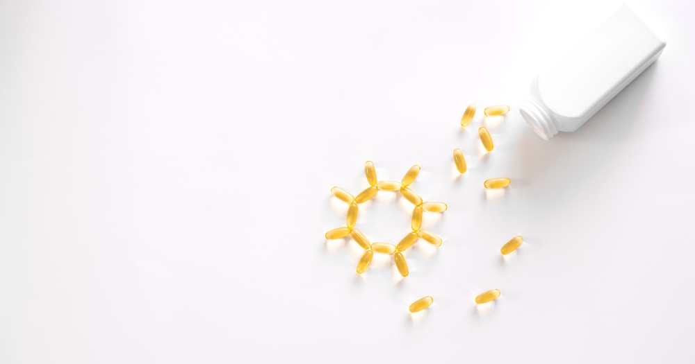 Yellow softgel capsules spilling from a white bottle onto a white surface