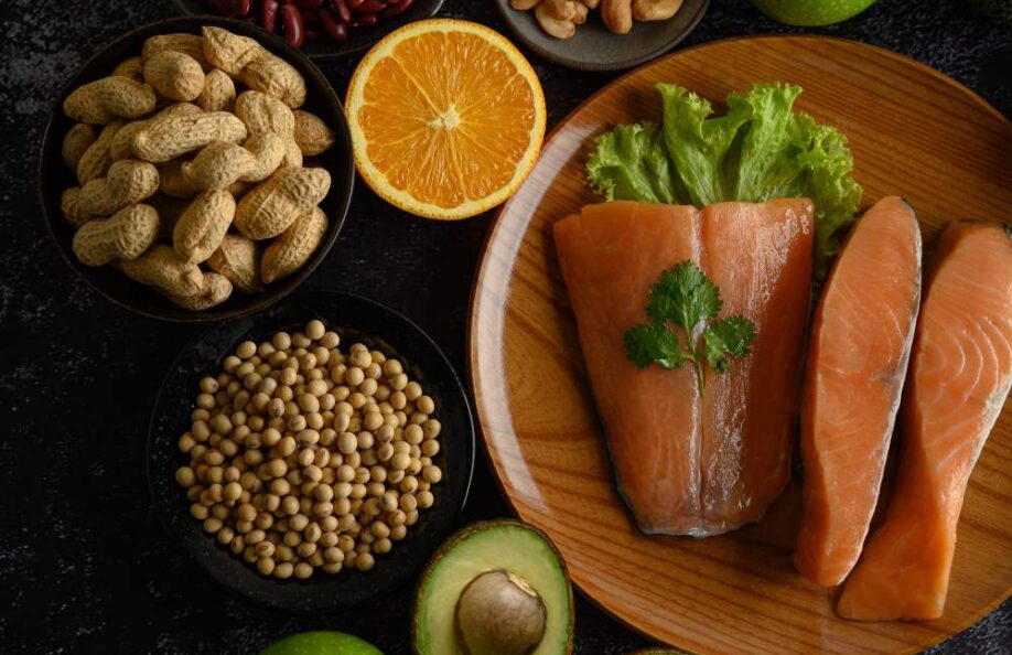 Salmon fillets, peanuts, chickpeas, orange and avocado on a dark table