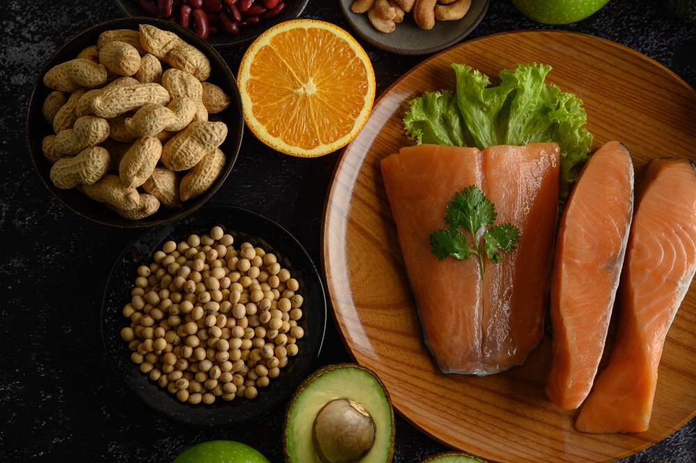 Salmon fillets, peanuts, chickpeas, orange and avocado on a dark table