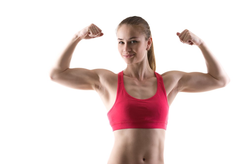 Healthy lifestyle: portrait of sporty young woman showing biceps muscles, studio shot, white background, isolated